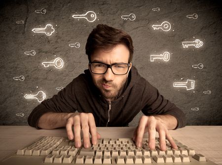 A young internet geek working online, hacking login passwords of social media users concept with glowing drawn keys on the wall