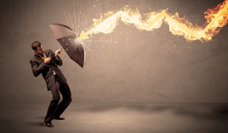 Business man defending himself from a fire arrow with an umbrella on grungy background