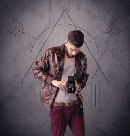 A young hipster male in modern clothes standing in front of an urban wall with modern sign illustration concept