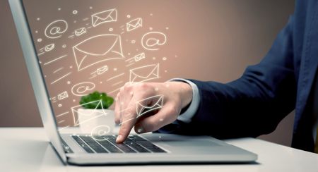 An office worker sending emails and communication with clients with the help of a portable laptop on desk concept