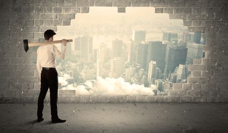 Business man hitting wall with hammer on city view background