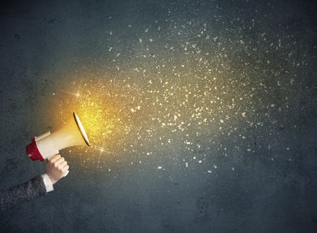 Caucasian business hand holding megaphone with yellow sparkles