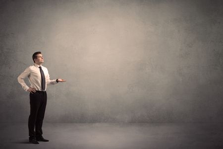 Caucasian businessman standing in front of a grunge, blank wall