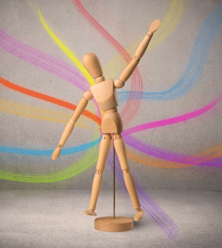 wooden-mannequin-posed-front-greyish-background-670190809 Wooden mannequin posed in front of a greyish background with colorful lines behind it