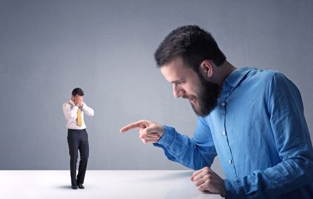 Young professional businessman being angry with an other miniature businessman 