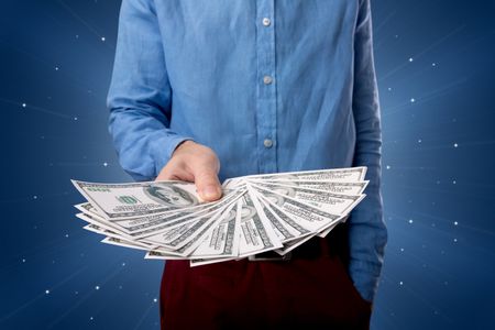 Young businessman holding large amount of bills with light beams behind him