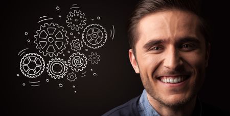 Portrait of a young businessman with rotating gears next to him on a dark background