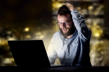 Young handsome businessman working late at night in the office with city lights in the background