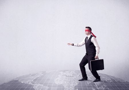 Young blindfolded businessman steps on a grey world map