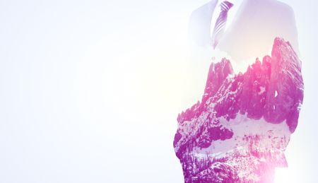 young-businessman-suit-standing-sunny-snowy-670211980 Young businessman in suit standing with sunny snowy mountain and trees graphic.