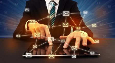Businessman in suit typing with connected mail icons around 