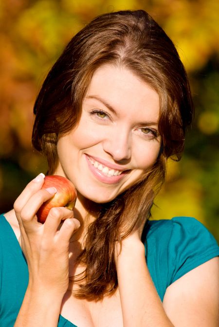 beautiful girl portrait with an apple in a park