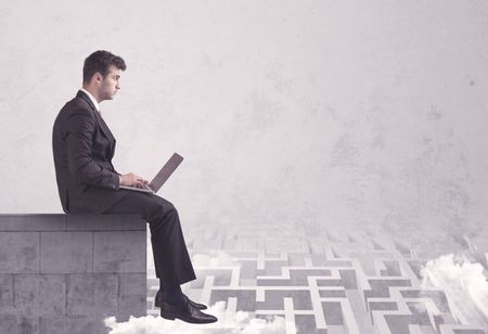 Business worker sitting on concrete building edge, thinking of solving a maze concept with labyrinth and clouds