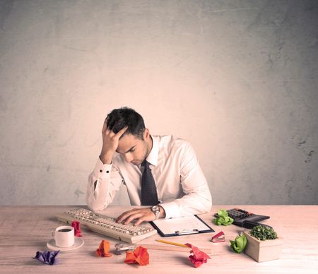 young-office-worker-sitting-desk-working-672695308 A young office worker sitting at desk working with keyboard, papers, highliter in front of empty clear background wall concept