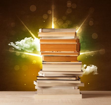 Magical books with ray of lights and colorful clouds on vintage background