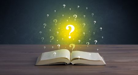 Yellow question marks hovering over open book 
