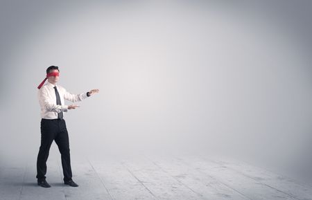 A young male business person in elegant dress standing with red blindfolds in a clear, empty space concept.