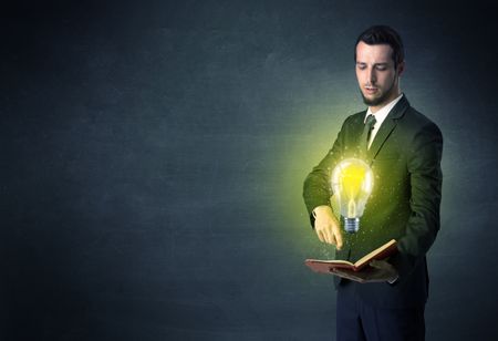 Businessman holding book with bulb.