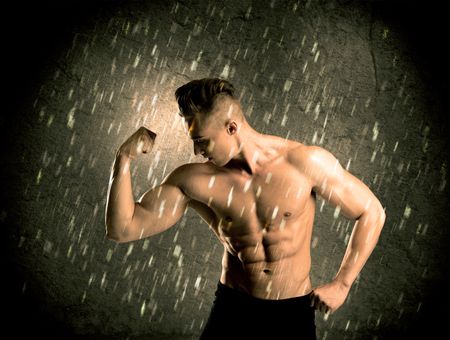 A handsome young body builder weightlifting while showing his muscular upper body in the rain concept
