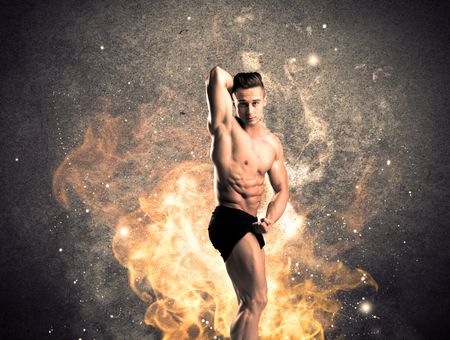 A strong athletic guy looking seductive while working out with weight in front of a burning fire concrete wall and big flames concept