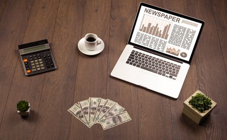 Business laptop with stock market report on wooden desk and accessories