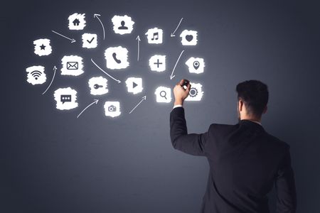 young-businessman-black-suit-standing-front-674015797 Young businessman in black suit standing in front of white multimedia icons