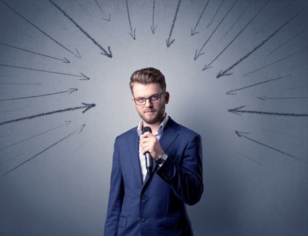 Businessman speaking into microphone with arrows pointing towards his head