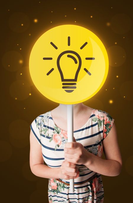 Casual young woman holding round sign with yellow lightbulb
