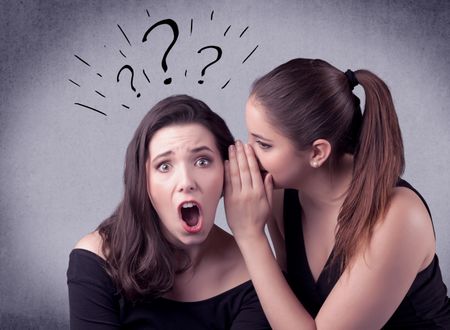 A teenager girl looking confused with drawn question marks above the head, while a girlfriend whispers something in her ear concept.