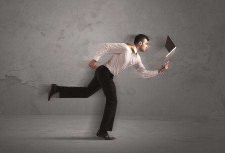 Running businessman in a rush with device in hand on background