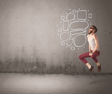 A comic hipster guy shouting in front of grey urban concrete wall with drawn empty text bubbles around his mouth concept