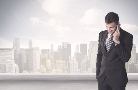 A young adult businessman standing in front of city landscape with skyscraper buildings and clouds concept