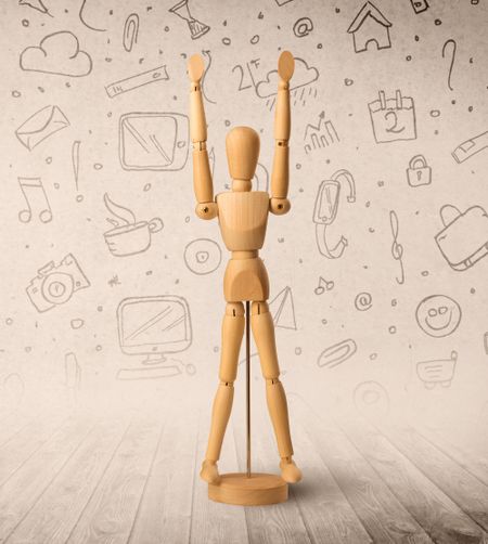 Wooden mannequin posed in front of a greyish background with mixed media scribbles behind it