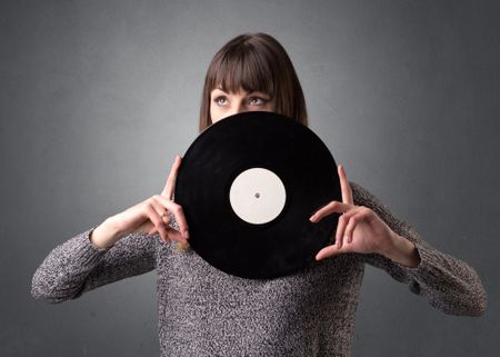 Young lady holding vinyl record on a grey background