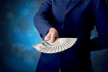 Young businessman holding large amount of bills with shiny blue background