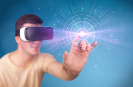 Young impressed man wearing virtual reality goggles with blue circles around his finger 