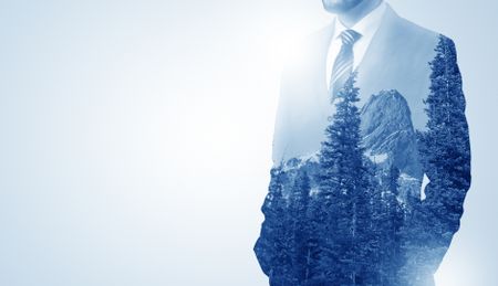 Young businessman standing and meditate with trees on the background 