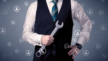 Thoughtful businesman holding tool with communication symbols around