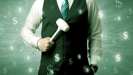 Handsome businessman holding tool with dollar symbols around and with green background