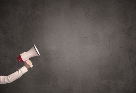 Caucasian arm holding megaphone with plain grunge background