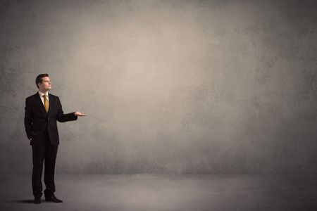 Caucasian businessman standing in front of a grunge, blank wall