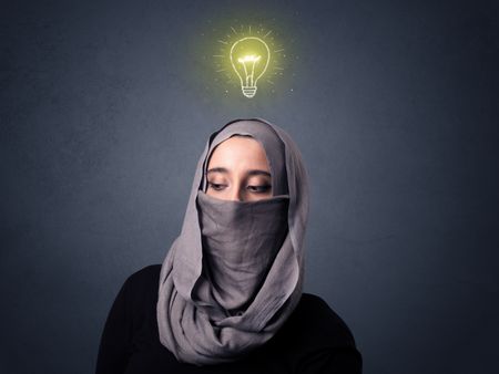 Young muslim woman wearing niqab with lit lightbulb above her head