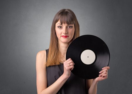 Young lady holding vinyl record on a grey background