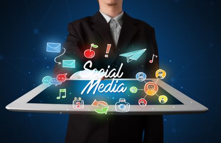 Casual businessman holding tablet with social media icons