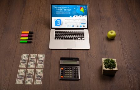 Laptop on office wooden desk with business website on screen