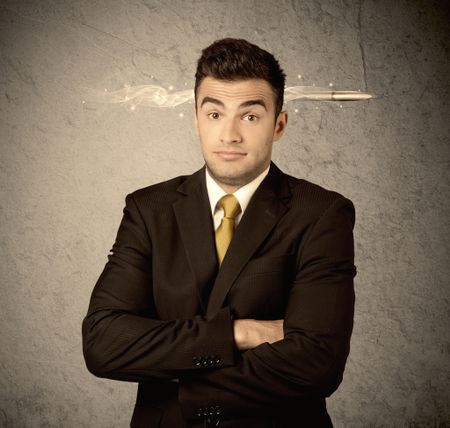 An elegant handsome business guy standing in front of wall with a bullet going through his head, making facial expressions concept