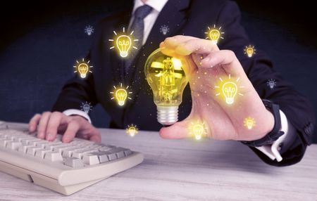 A creative businessman has a bright idea concept with office worker holding light bulb in foreground.