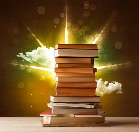 Magical books with ray of lights and colorful clouds on vintage background