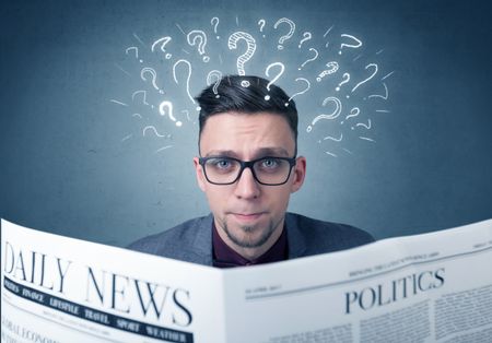 Young confused businessman reading daily newspaper with question marks above his head