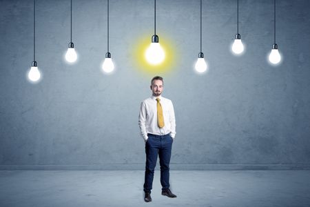 Handsome businessman in an empty space with bulbs above and uninspired face
